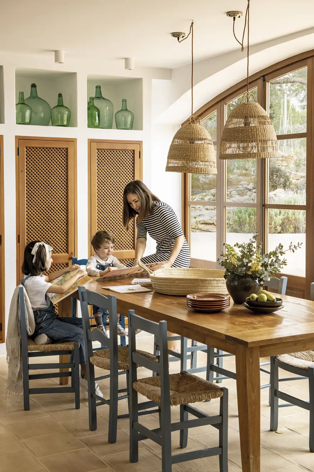 Comedor de la cocina con mesa y sillas de madera, familia leyendo libros, mueble empotrado con puerta con celosía